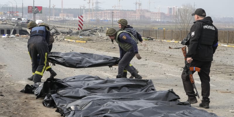 Ukrajinští vojáci sbírají těla třinácti civilistů zabitých ruskými silami na zničeném mostě ve městě Irpiň nedaleko Kyjeva. (31. března 2022)