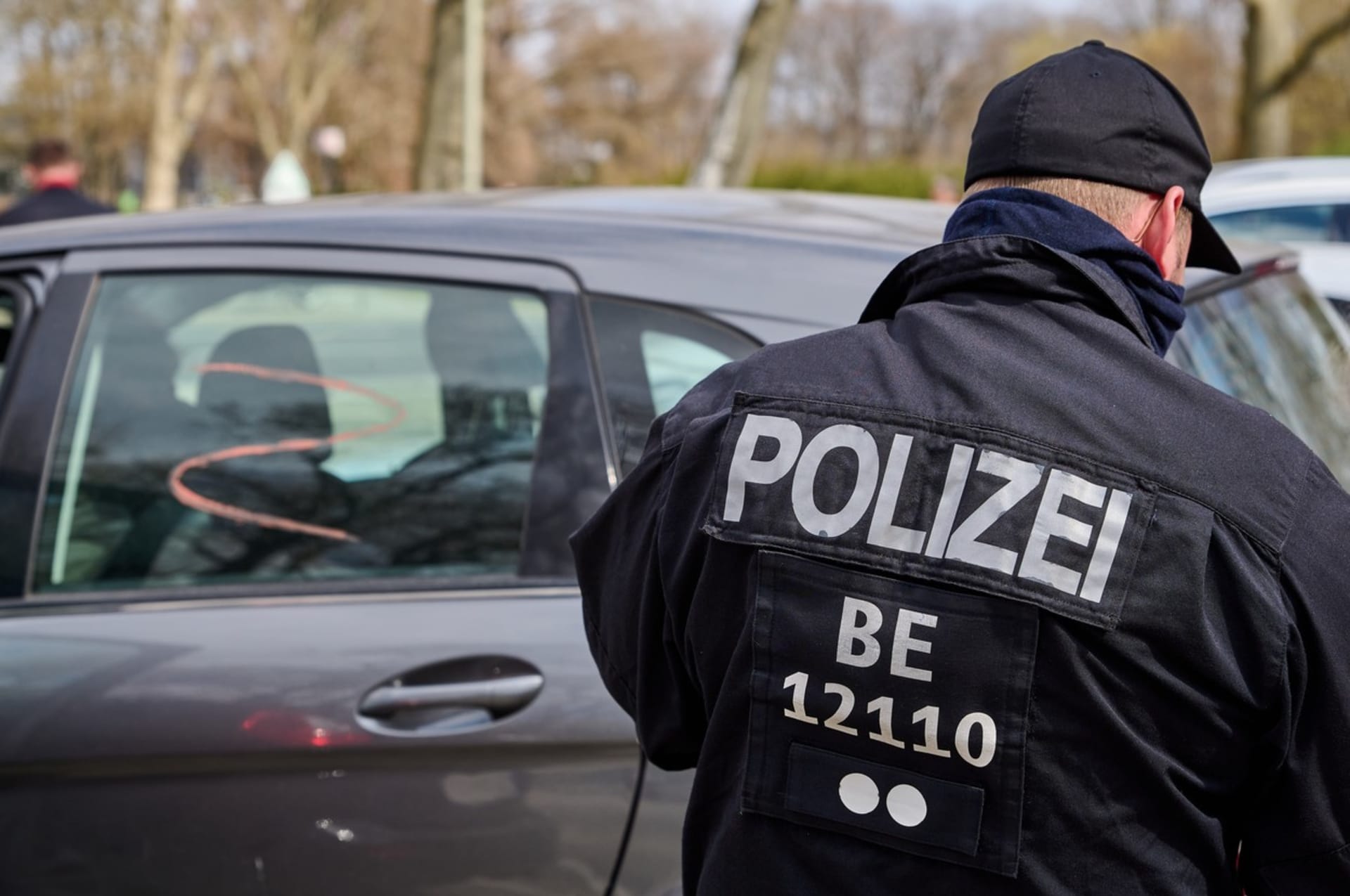Policista v Berlíně kontroluje účastníky auto korza s ruskými symboly, které projelo v neděli 3. dubna 2022 německým hlavním městem.