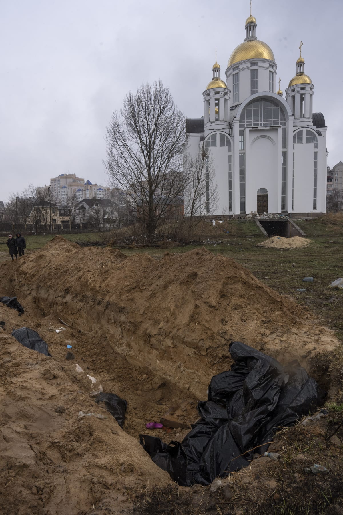 V nezahrnutém hromadném hrobu u kostela byly vidět kusy těl, ruce, nohy, informovali zpravodajové z místa.