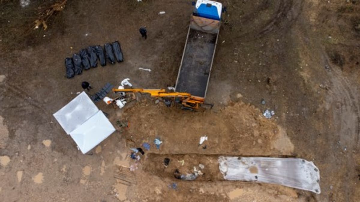 Vynášení těl z masového hrobu v Buči k následné identifikaci obětí