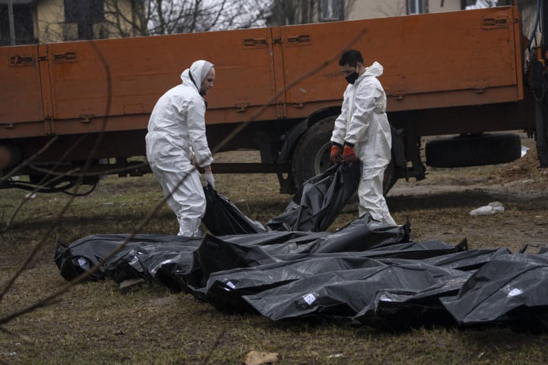 Zaměstnanci hřbitova vyzvedávají těla z masového hrobu v Buči, aby mohla být identifikována.