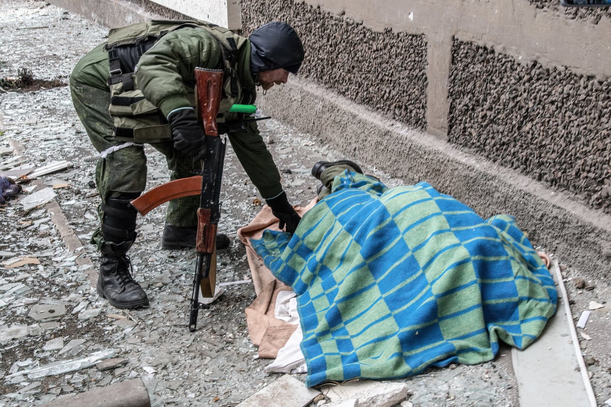 Voják se naklání k mrtvému tělu v Mariupolu. (9. dubna)