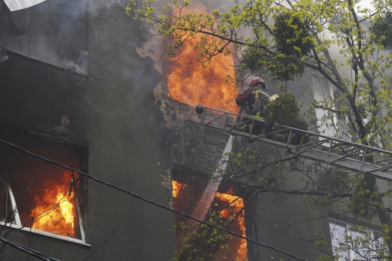 Hasiči likvidují požár obytného domu po ostřelování Charkova.