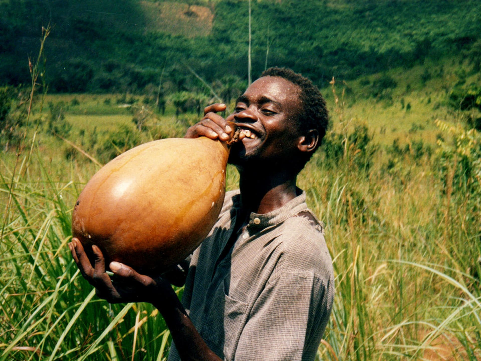 vysmátý mladík z Konga se osvěžuje palmovým vínem