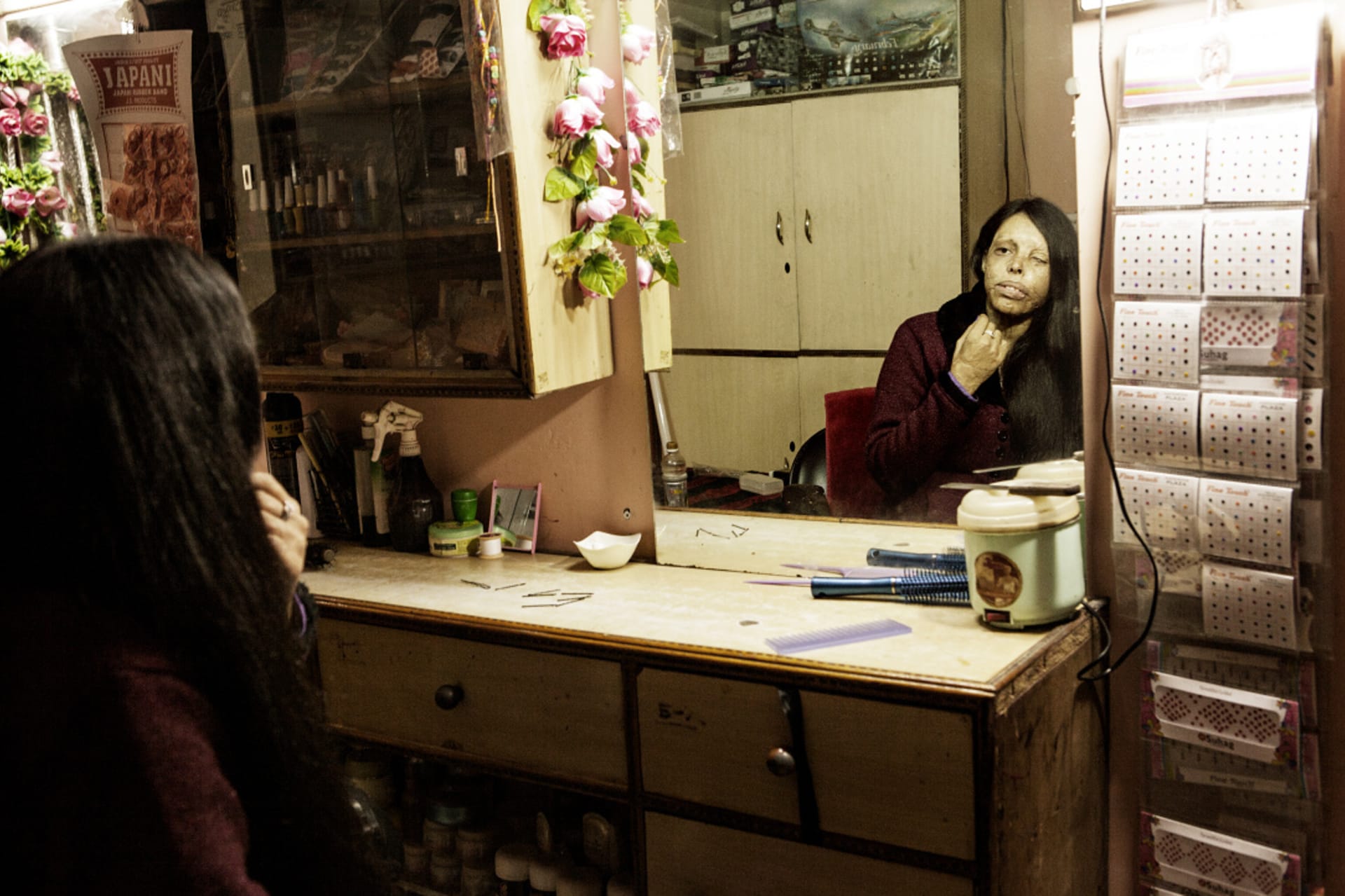 Indická dívka politá kyselinou - se prohlíží v zrcadle
