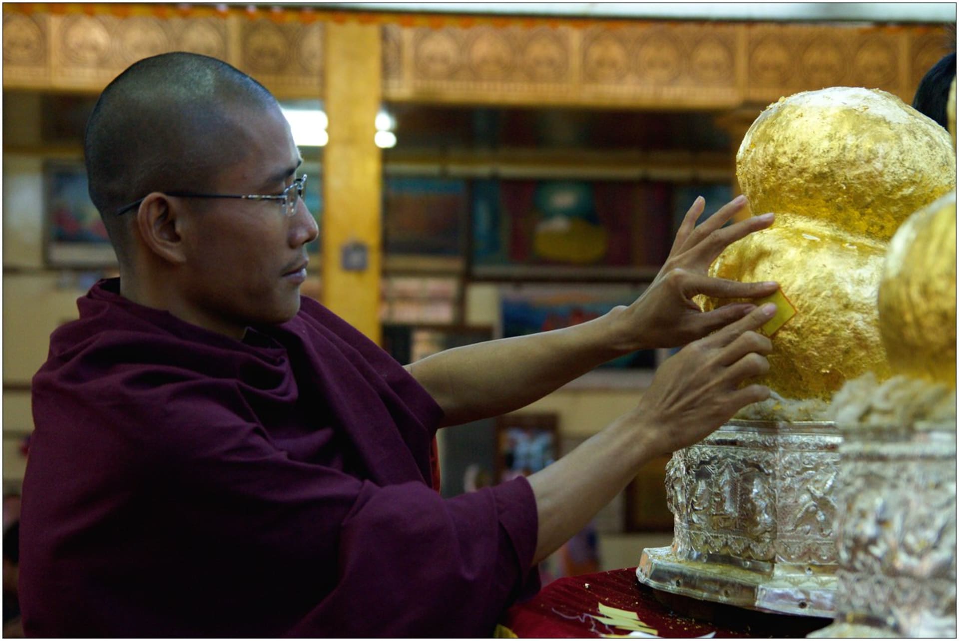 Lepení zlatých plíšků na Buddhy vylovené ze dna jezera