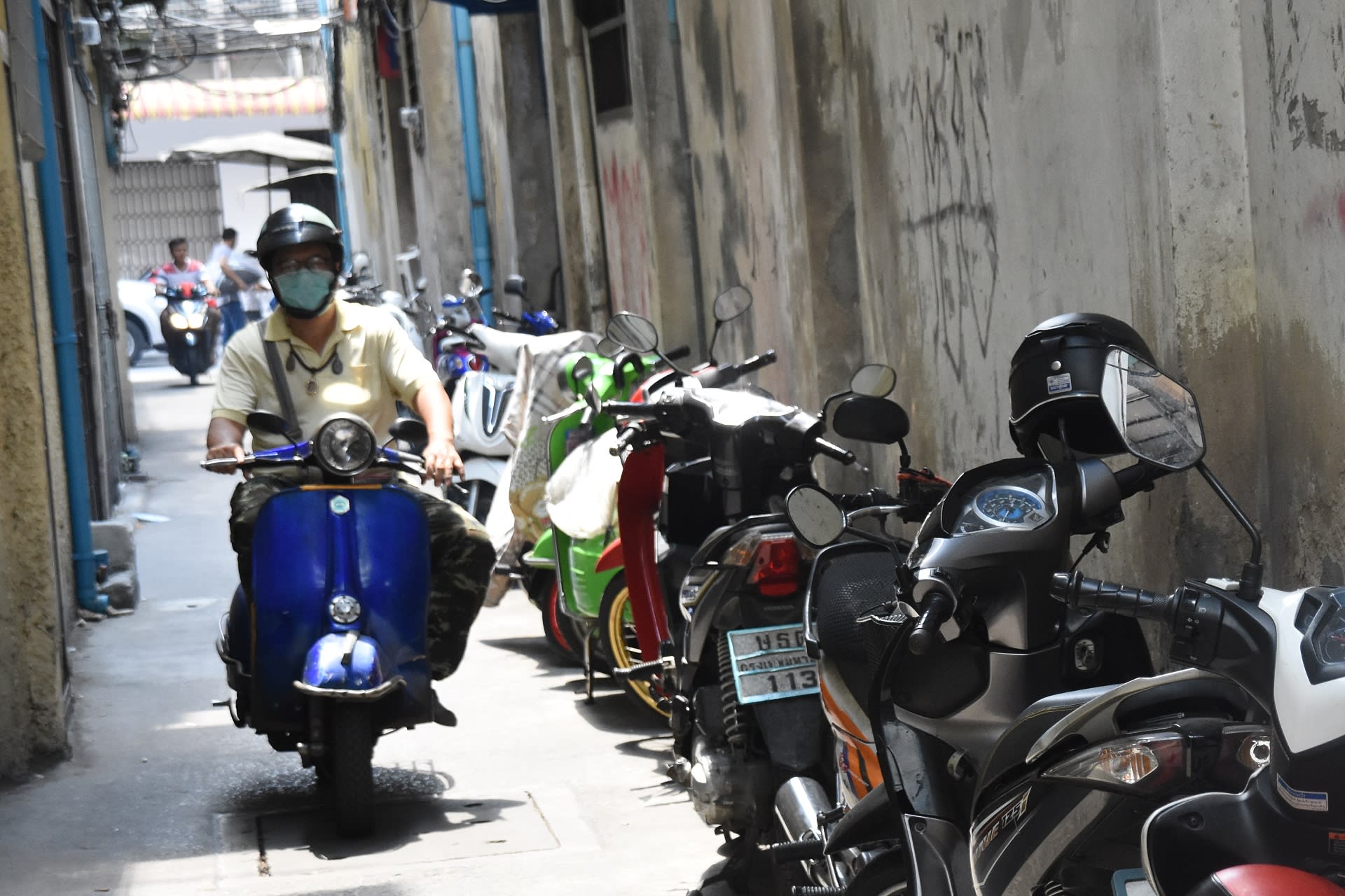 S rouškou na motorce v ulicích Bangkoku