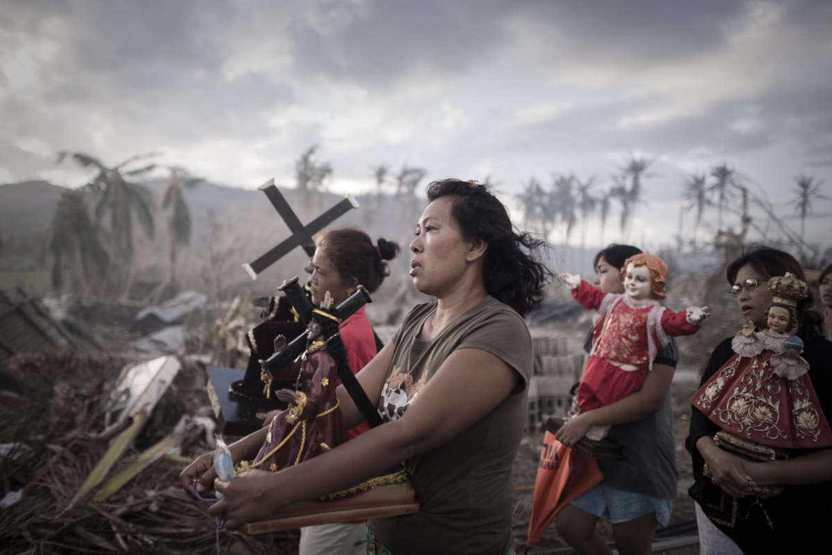 Deset dnů poté, co tajfun Haiyan dorazil na ostrov Leyte ve střední části Filipín, nesou přeživší obyvatelé Tolosy v průvodu náboženské předměty.