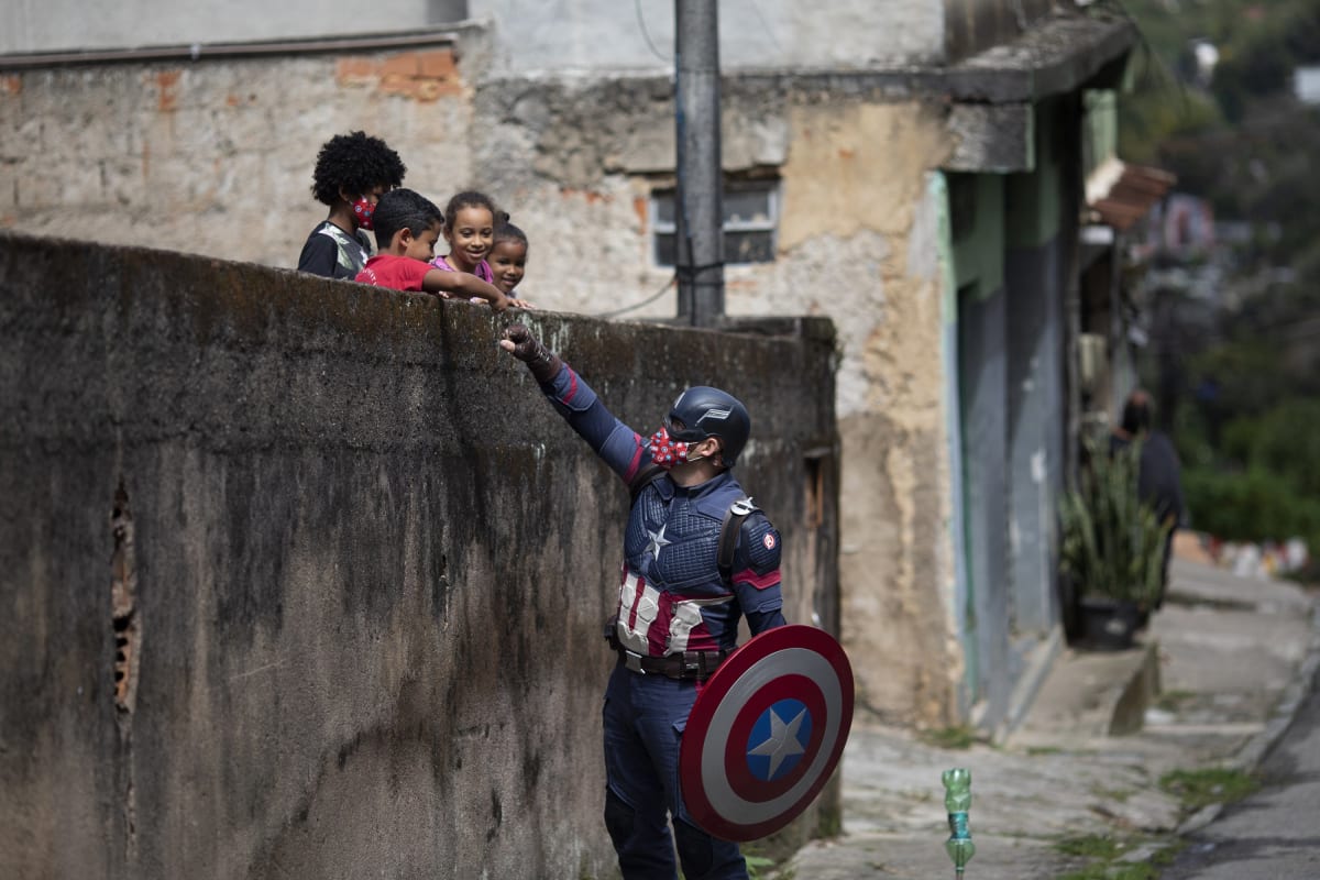 Policista Everaldo Pinto v brazilském Rio de Janeiru oblečený jako Kapitán Amerika se 15. dubna 2021 zdraví s dětmi a povzbuzuje je během pandemie covid-19
