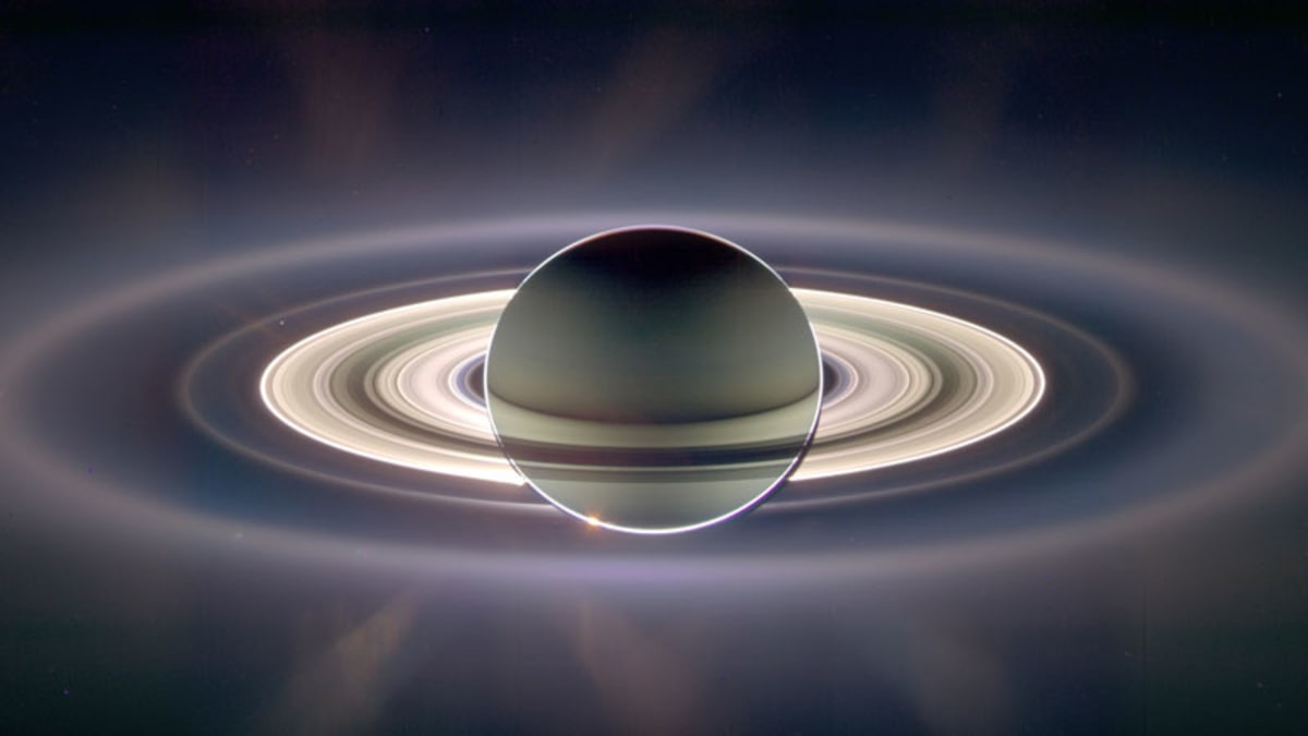 : Saturn jak jej vidí vesmírná sonda Cassini proti Slunci. Peggy se vytvořila na vnějším okraji jasných prstenců. Na snímku je nicméně vidět mnoho dalších méně jasných prstenců, které dávají tušit dávné existenci mnohem většího prstencového komplexu