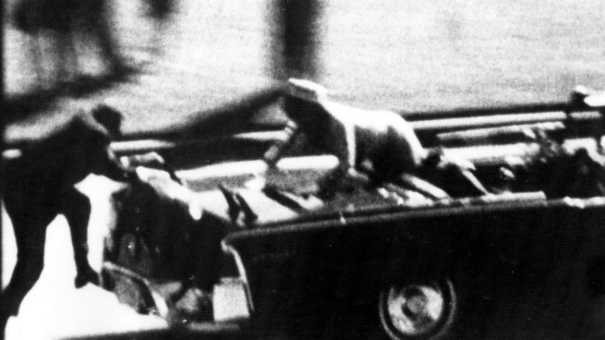 Krátce po atentátu - Jackie Kennedyová volá o pomoc pro smrtelně zraněného manžela, zezadu se snaží naskočit člen ochranky.
