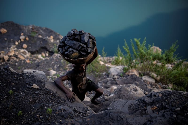 Muž zdolává 24. září 2021 prudký svah poblíž průmyslového města Dhanbádu ve východoindickém státě Džhárkhand s košem uhlí na rameni. Právě v tomto státě se nacházejí největší indická ložiska uhlí