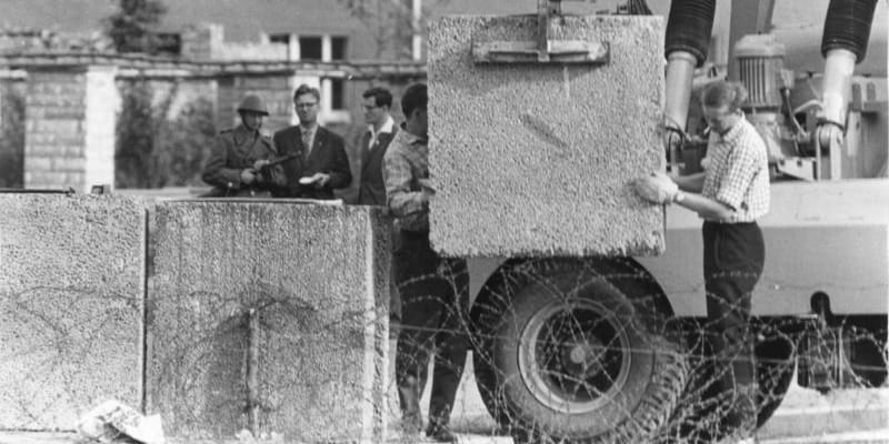 Stavbaři umisťují první betonové bloky dosud provizorní Berlínské zdi (srpen 1961)