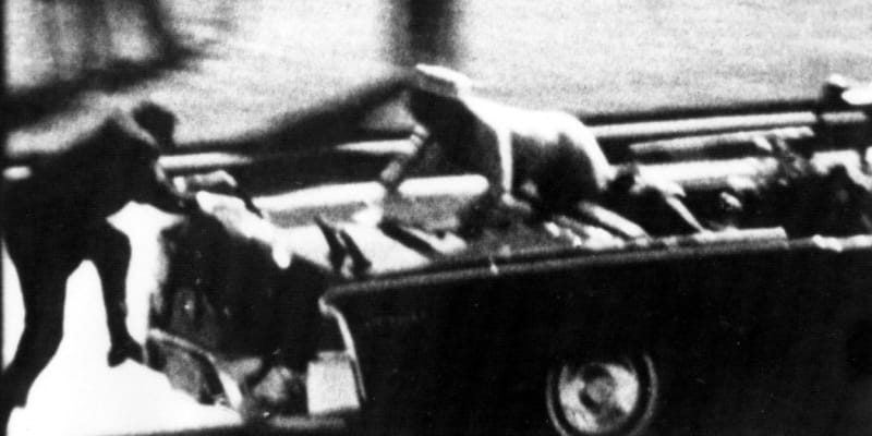 Krátce po atentátu – Jackie Kennedyová volá o pomoc pro smrtelně zraněného manžela, zezadu se snaží naskočit člen ochranky.