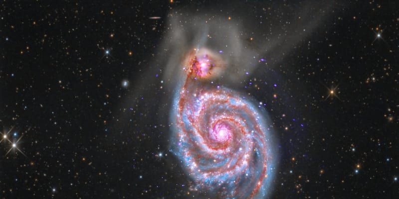 Spirálová galexie M51 se právě spojuje s menší galaxií (nahoře)