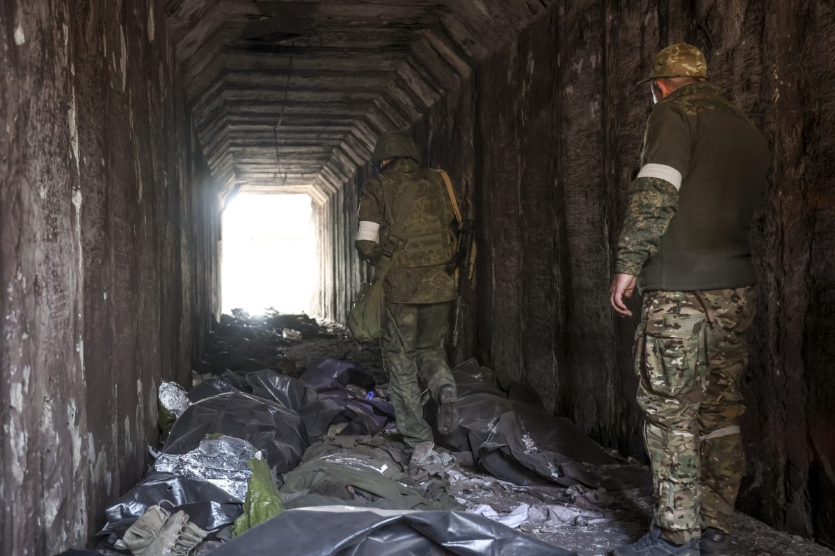 Proruští separatisté prochází tunelem kolem mrtvých těl v Mariupolu. (18. dubna)