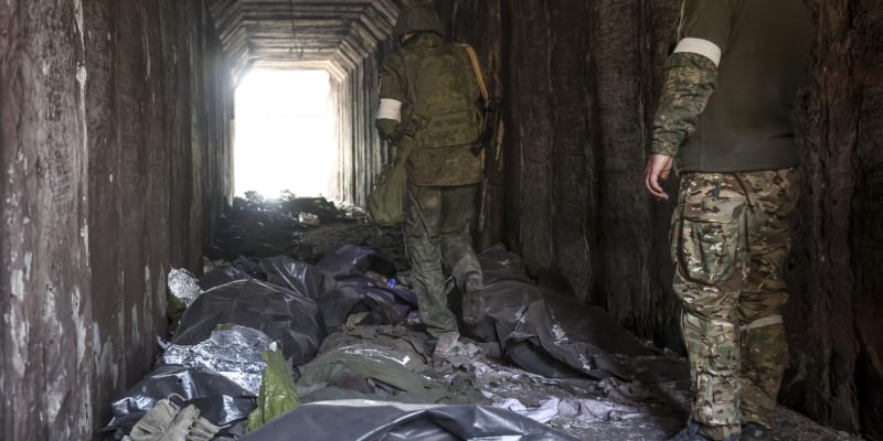 Proruští separatisté prochází tunelem kolem mrtvých těl v Mariupolu. (18. dubna)