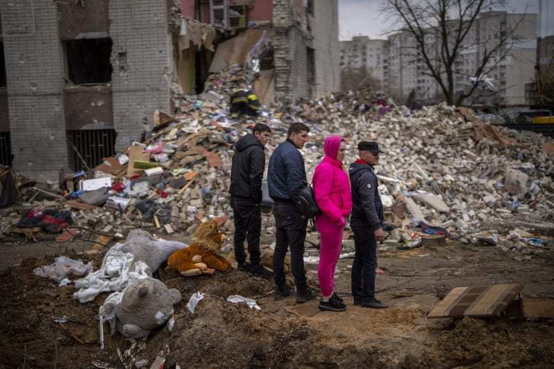 Lidé koukají na trosky obytného domu v Černigově, který zasáhla ruská bomba. (22. dubna 2022)