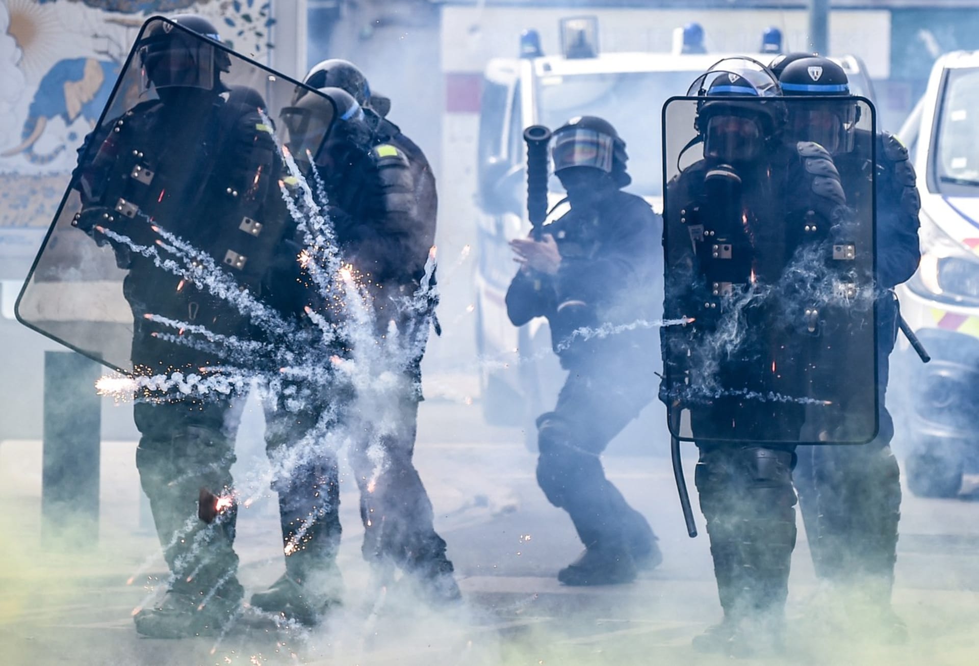 Francouzští policisté se chrání před zábavní pyrotechnikou házenou protestujícími na okraji tradičního prvomájového shromáždění v Nantes.