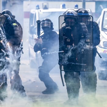 Francouzští policisté se chrání před zábavní pyrotechnikou házenou protestujícími na okraji tradičního prvomájového shromáždění v Nantes.