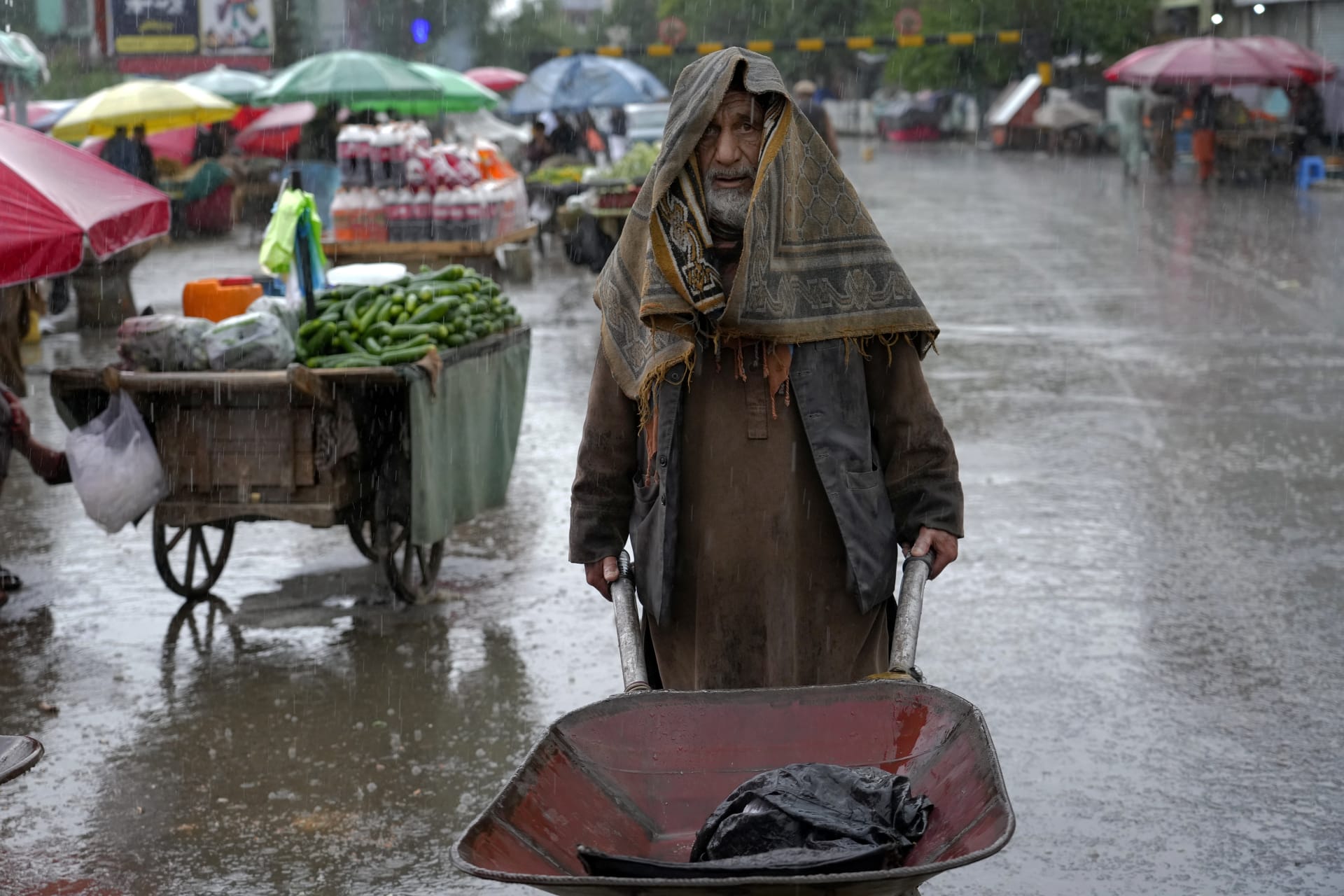 Afghánský dělník tlačí trakař během deštivého dne na starém trhu v Kábulu v Afghánistánu, úterý 3. května 2022. 
