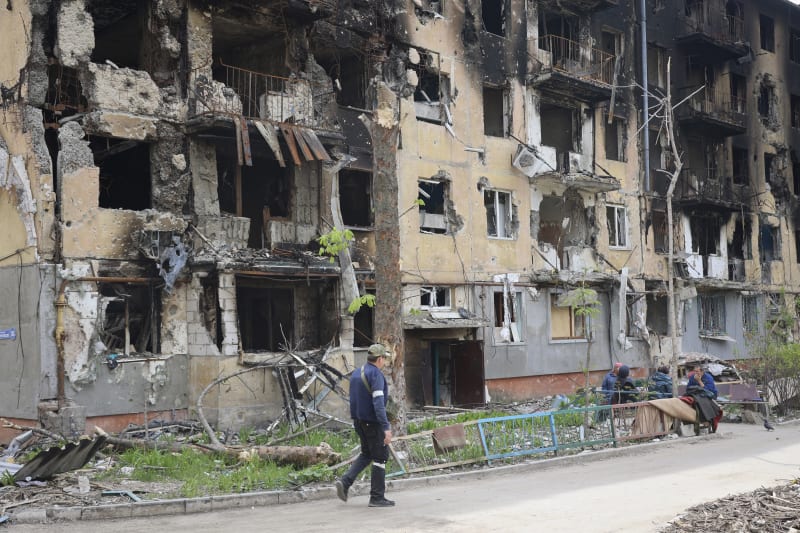 Muž prochází před těžce poškozenou budovou v části Mariupolu, kterou kontrolují síly tzv. Doněcké lidové republiky
