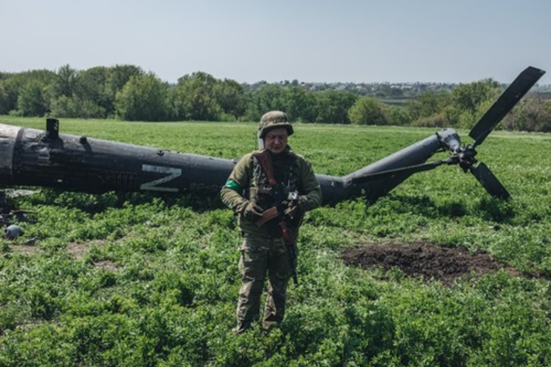 Ukrajinský voják u sestřelené ruské helikoptéry poblíž Charkova