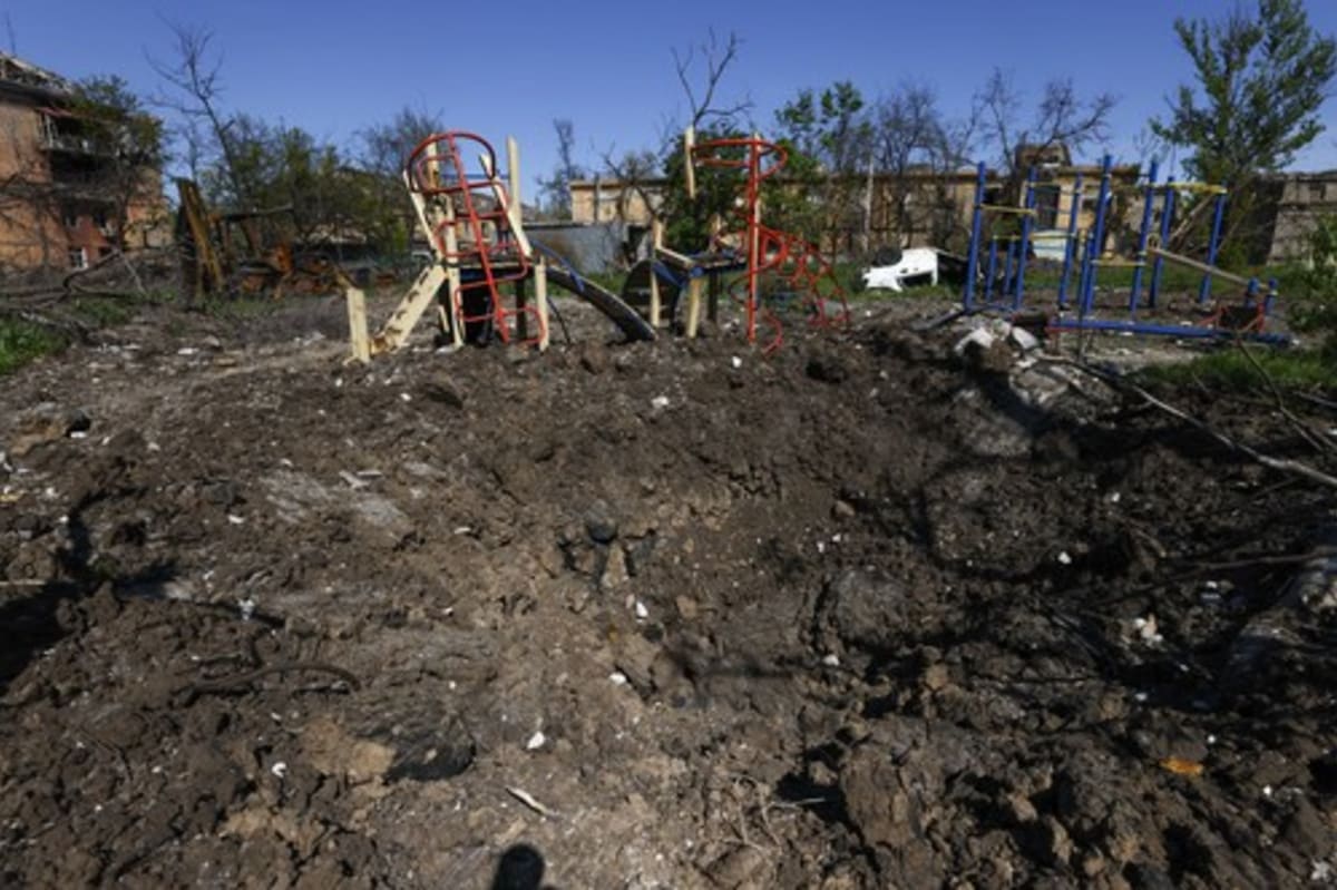 Kráter po dopadu dělostřeleckého granátu na dětském hřišti v Mariupolu