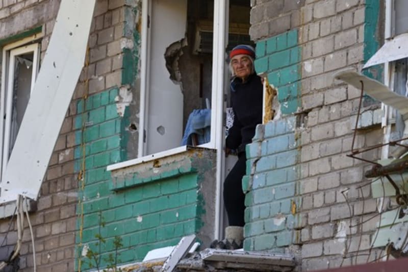 Obyvatelka Mariupolu vyhlíží ze zbytků svého bytu (8. 5.)