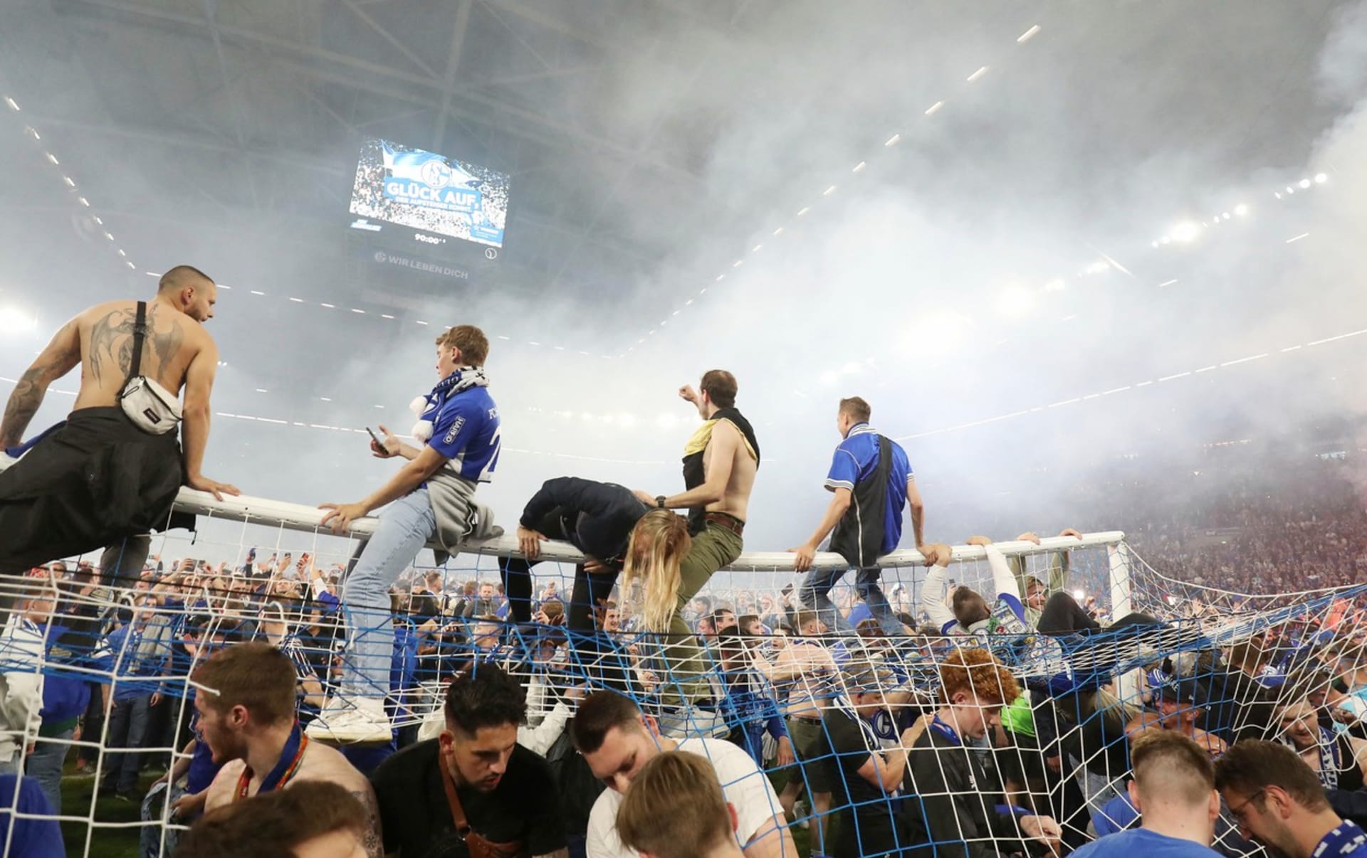 Fanoušci německého fotbalového klubu Schalke 04 sedí po vítězném utkání 3:2 nad FC St. Pauli ve druhé bundeslize na brance ve Veltins Areně v Gelsenkirchenu. Oslavovali tak postup do nejvyšší soutěže. Na tribunách však někteří lidé bojovali o život. 