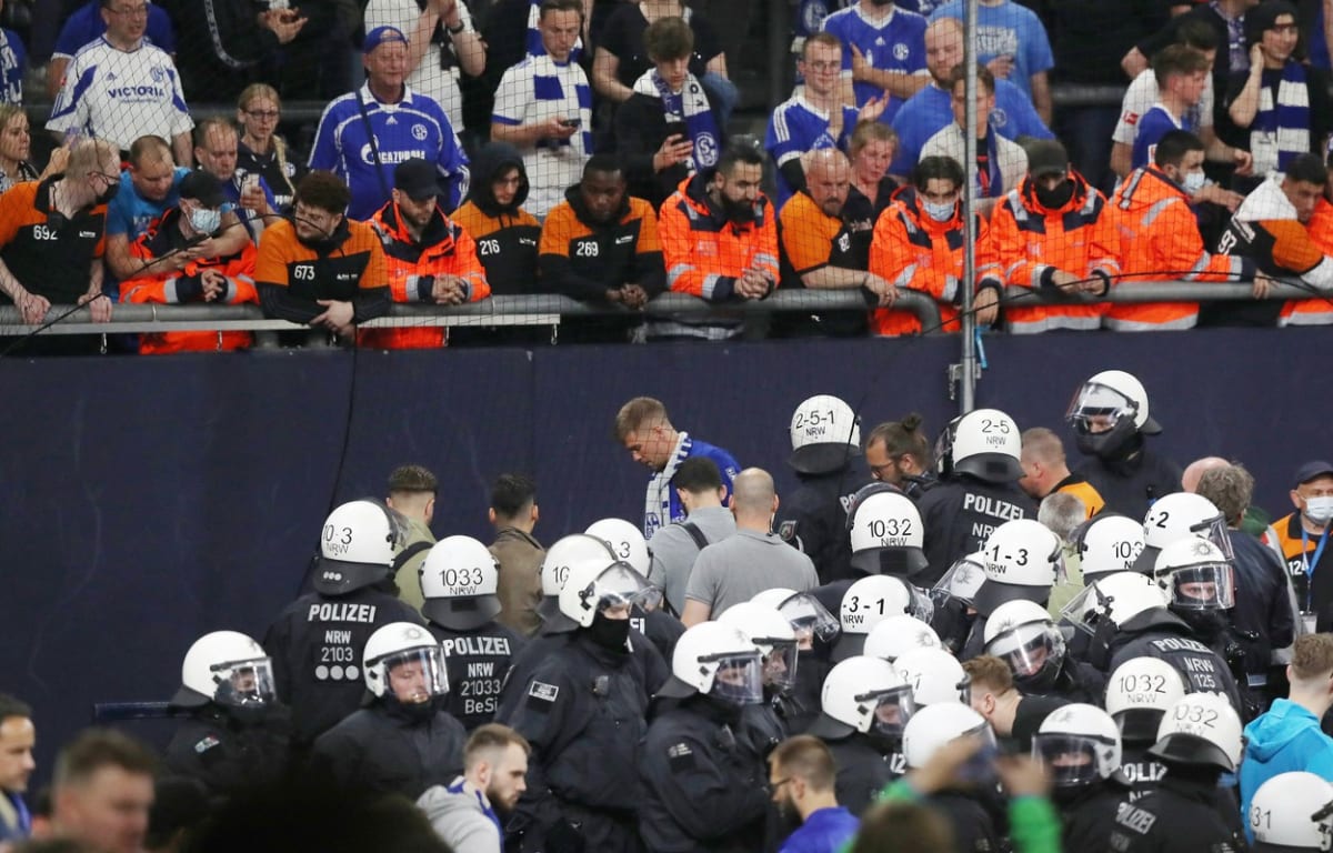Pracovníci bezpečnostní služby Stölting Gruppe v oranžových vestách a policisté sledují dění na tribuně Veltins Areny v Gelsenkirchenu po utkání druhé německé bundesligy mezi Schalke 04 a FC St. Pauli. Domácí tým vyhrál 3:2 a po roce se vrací do nejvyšší soutěže. 