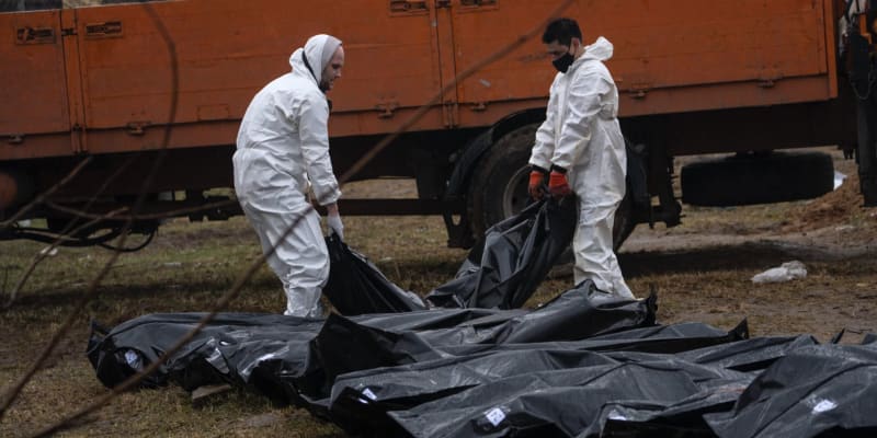 Zaměstnanci hřbitova vyzvedávají těla z masového hrobu v Buči, aby mohla být identifikována.