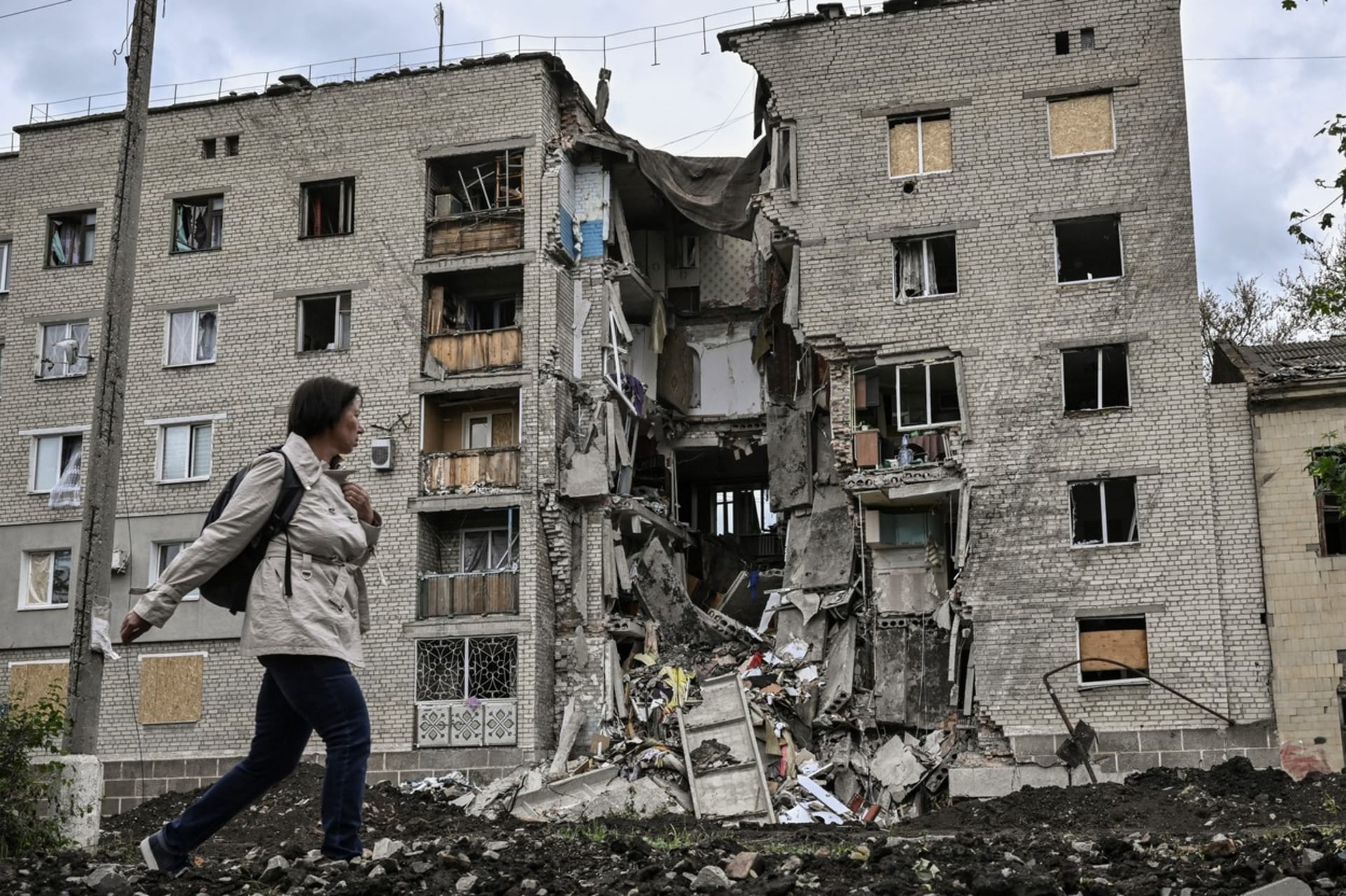 Žena prochází okolo zničeného domu ve městě Bachmut na východě Ukrajiny.