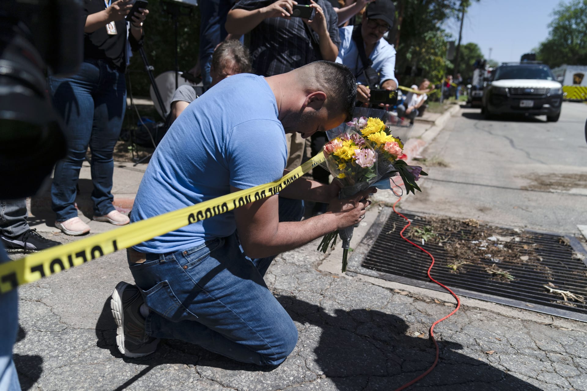Muž s kyticí v ruce se modlí nedaleko místa masakru na texaské základní škole