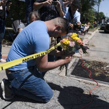 Muž s kyticí v ruce se modlí nedaleko místa masakru na texaské základní škole