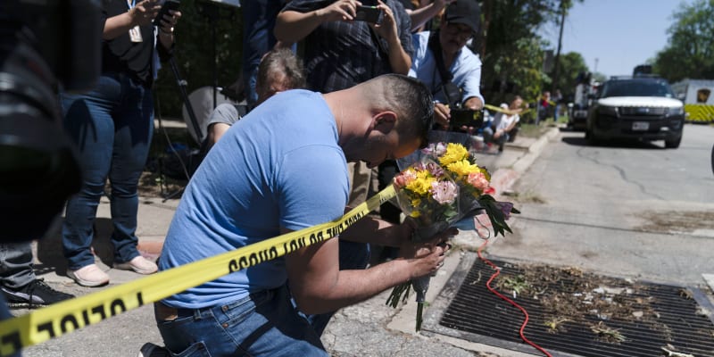 Muž s kyticí v ruce se modlí nedaleko místa masakru na texaské základní škole.