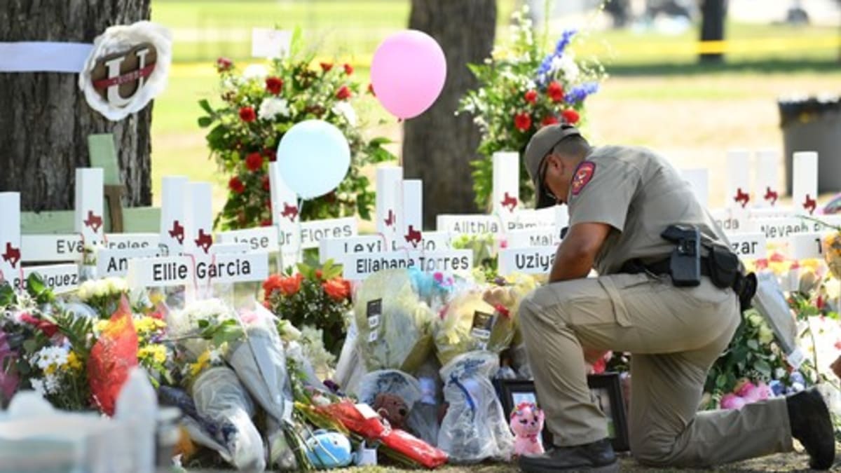 Policista klečí u pietního místa za oběti masakru na texaské základní škole v Uvalde