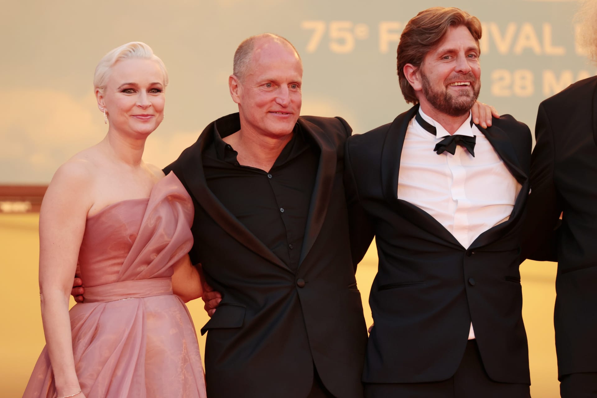 Herečka Vicki Berlinová, herec Woody Harrelson a režisér Ruben Östlund odcházejí z promítání svého vítězného snímku Triangle of Sadness.