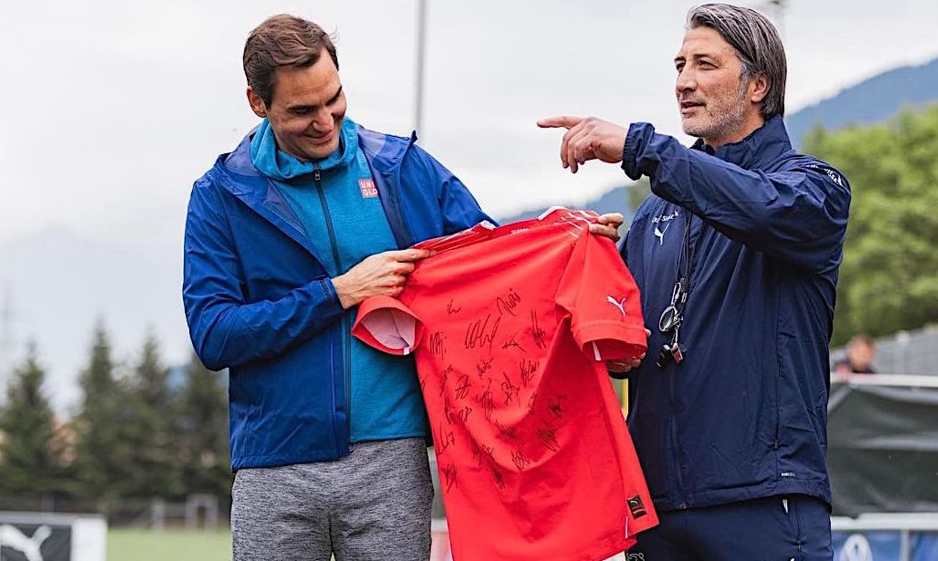 Trenér švýcarské fotbalové reprezentace Murat Yakin (vpravo) předává tenistovi Rogeru Federerovi podepsaný dres od všech hráčů na soustředění v Bad Ragazu před zápasem Ligy národů v Praze proti Česku.