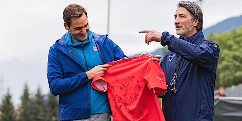 Trenér švýcarské fotbalové reprezentace Murat Yakin (vpravo) předává tenistovi Rogeru Federerovi podepsaný dres od všech hráčů na soustředění v Bad Ragazu před zápasem Ligy národů v Praze proti Česku.