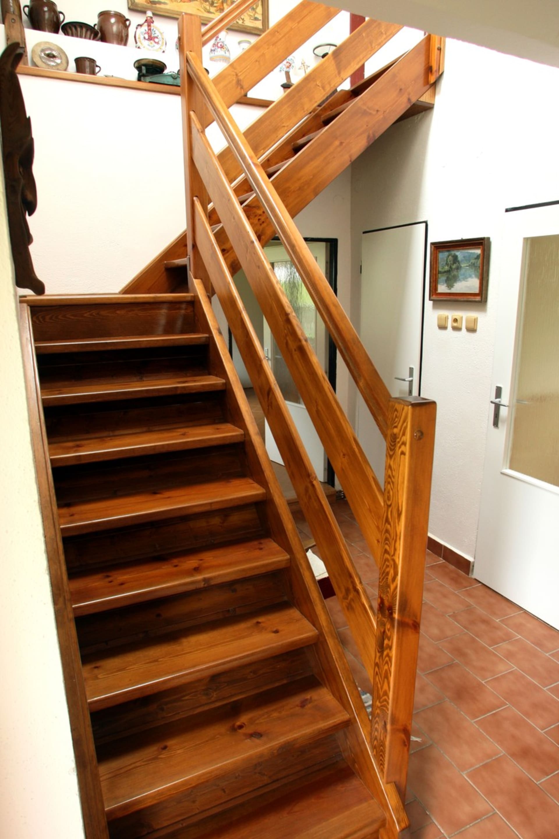 Do horního patra vede úzké dřevěné schodiště, podél něhož jsou vystaveny různé předměty.