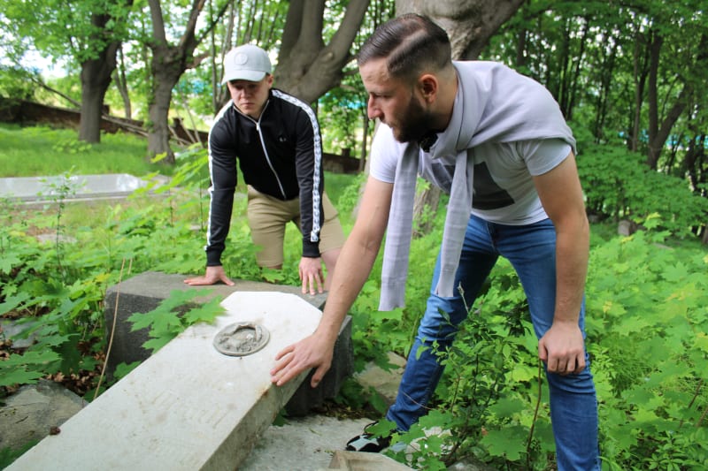 Německý hřbitov v Krnově-Chomýži. Aktivisté Martin Chalupa a Matěj Plaček ukazují jeho žalostný stav.