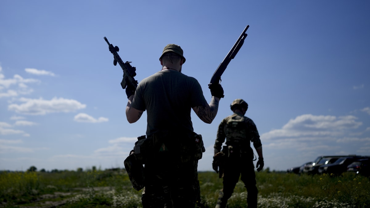 Člen ukrajinské civilní milice drží brokovnici a pušku během výcviku na předměstí Kyjeva.