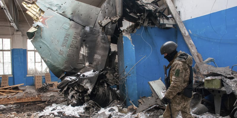 Ukrajinský voják stojí u úlomků sestřeleného ruského bombardéru Suchoj Su-34. 