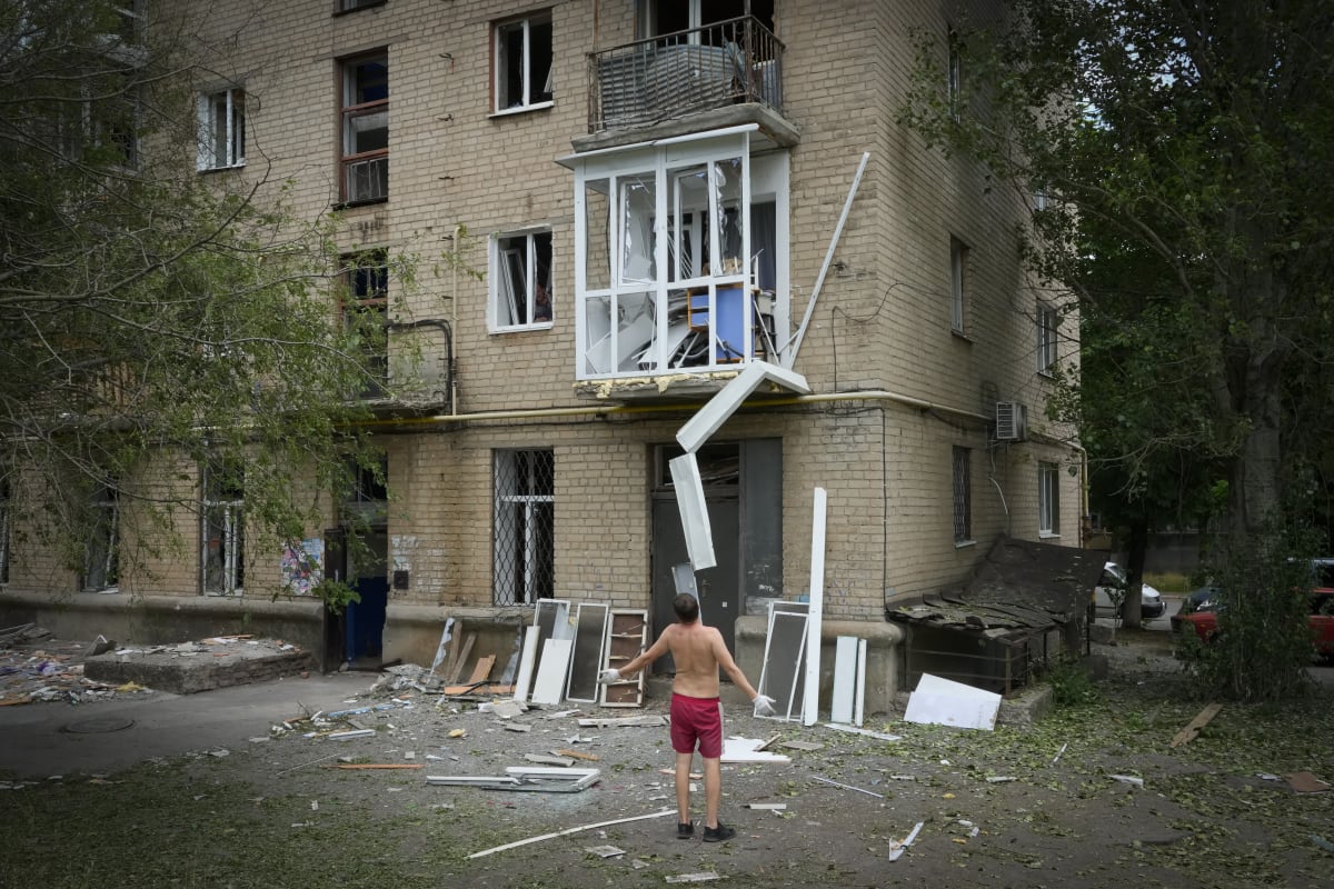 Muž stojící před poničeným domem po ruském ostřelování města Bachmut v Doněcké oblasti