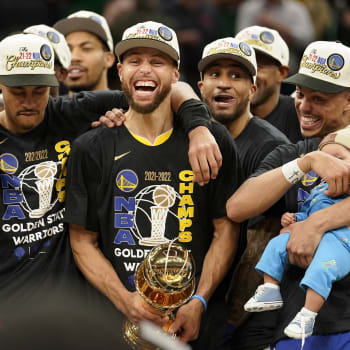 Hráč Golden State Warriors Stephen Curry (uprostřed) se raduje se z trofeje Billa Russella pro nejužitečnějšího hráče. (16. června 2022 v Bostonu)