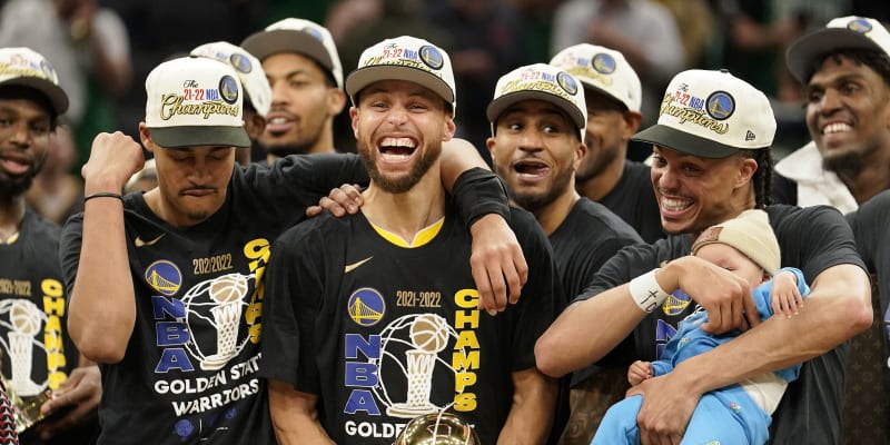 Hráč Golden State Warriors Stephen Curry (uprostřed) se raduje z trofeje Billa Russella pro nejužitečnějšího hráče. (16. června 2022 v Bostonu)
