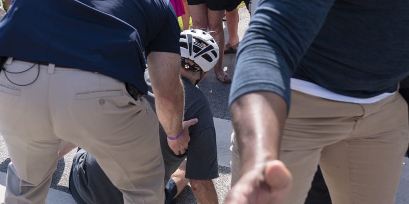 Prezidentovi Joe Bidenovi pomáhají agenti americké tajné služby poté, co spadl z kola, když se snažil sesednout, aby pozdravil dav na stezce u rybníka Gordons Pond v Rehoboth Beach, Del., sobota 18. června 2022. 