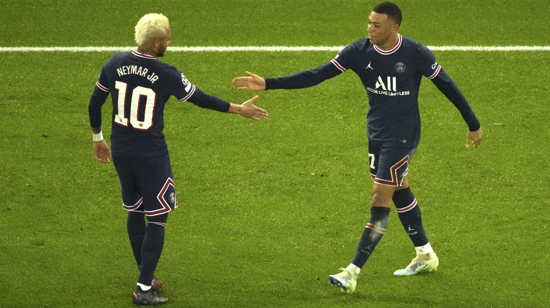 Brazilský útočník Neymar (vlevo) blahopřeje tlesknutím rukou svému spoluhráči z Paris Saint-Germain k jeho vstřelenému gólu Realu Madrid v prvním kole play-off Ligy mistrů 2021–2022. 