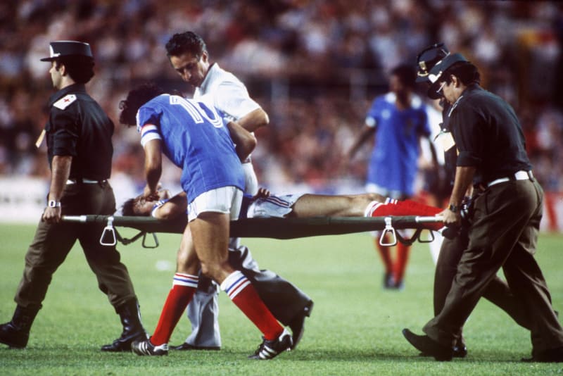 Policisté odnášejí na nosítkách francouzského fotbalistu Patricka Battistona po střetu s německým brankářem v semifinále mistrovství světa 1982 ve španělské Seville. 